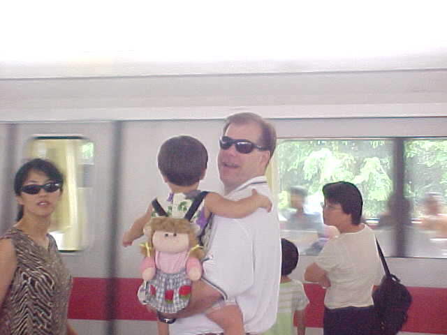 Ling Cave CC Cave (in bill's arms) and Bill cave boarding a Singapore subway train (Singapore, The Travel Addicts)
